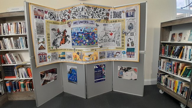 A grey display board hosts a large piece of artwork in the middle of the library.