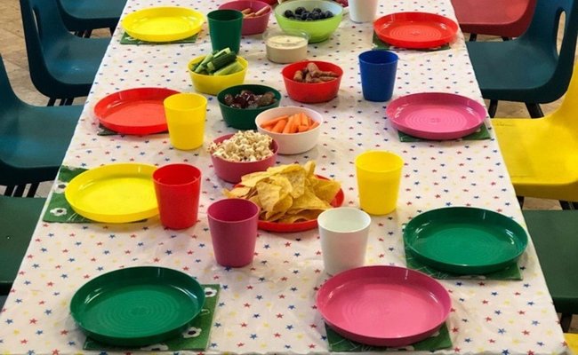 A party table set up for food using colourful reusable plates