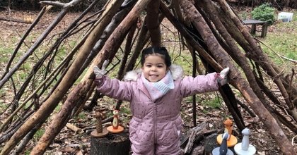 Young child standing inside a den built of sticks