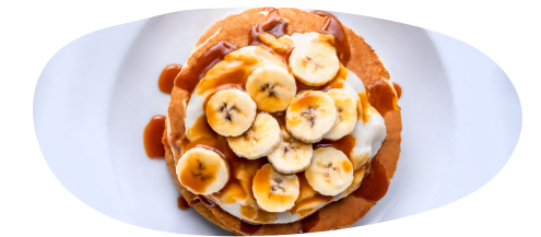 Aerial view of a stack of pancakes topped with sliced banana and syrup