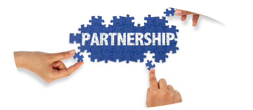 Jigsaw pieces with two hands building the puzzle which says partnerships