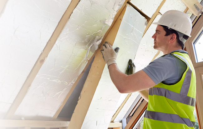 Image of man insulating a house roof.